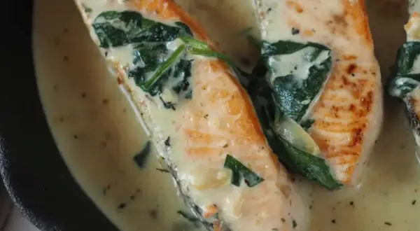 Saftiger Lachs mit Spinat in cremiger Sauce, garniert mit Tomatenstücken. Ein köstliches Gericht, das Lust auf mehr macht.