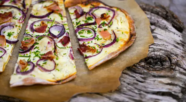 Flammkuchen mit Zwiebeln, Speck und Schnittlauch. Ein klassisches rezept flammkuchen belag, das immer schmeckt.