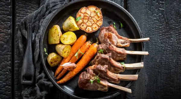 Saftiges Lammkarree mit Rosmarinkartoffeln, Karotten und geröstetem Knoblauch – das beste Rezept für einen Festtagsschmaus.