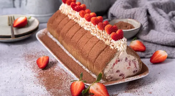 Erdbeer Tiramisu Rolle mit frischen Erdbeeren und Kakao bestäubt, ein Genuss für Augen und Gaumen.