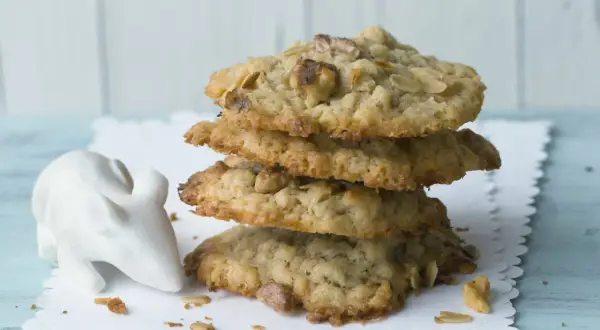 Ein Stapel leckerer cookies mit haferflocken und schokolade, daneben eine kleine weiße Maus-Dekoration.