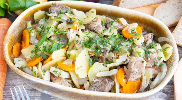 Herzhaftes Baeckeoffe Rezept Original: deftiger Eintopf mit Kartoffeln, Karotten und Fleisch, garniert mit Petersilie.