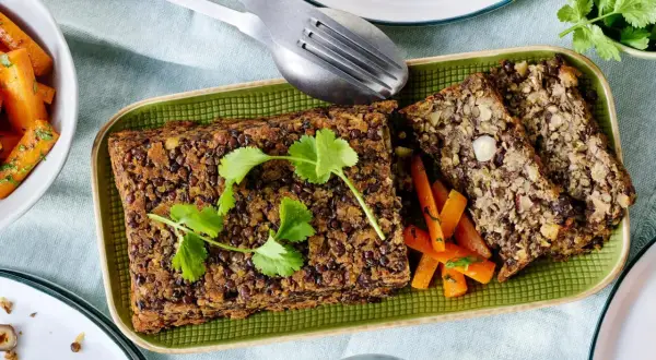 Herzhafte Linsen-Nuss-Braten, perfekt für vegetarische Rezepte Weihnachten. Dazu karamellisierte Karotten und frische Kräuter.