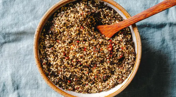 Schale mit selbstgemachtem Furikake, einer Mischung aus geröstetem Sesam, Algen und Chili. Ein Holzspatel liegt darin.