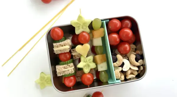 Bento-Box mit Spießen aus Mini-Sandwiches, Gurkensternen, Tomaten und Käseherzen. Ein tolles bento rezept für Kinder.