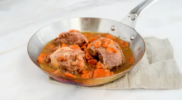 Saftige Daube de boeuf mit Karotten in einer Pfanne, serviert auf einem Leinentuch.