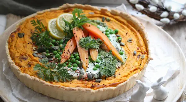 Herzhafte quiche mit pfifferlingen, garniert mit Erbsen, Karotten, Zitrone und Kräutern. Ein frühlingshafter Genuss!