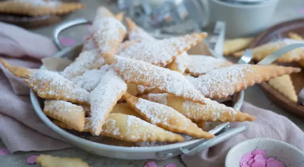 Leckere, knusprige Mutzen, bestäubt mit Puderzucker, warten auf Genießer. Was sind Mutzen? Diese frittierten Teigteilchen sind ein süßer Genuss!