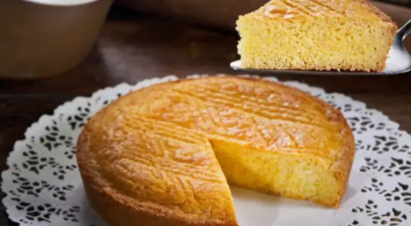 Ein goldbraunes Gateau Breton mit einem Stück auf einem Tortenheber.