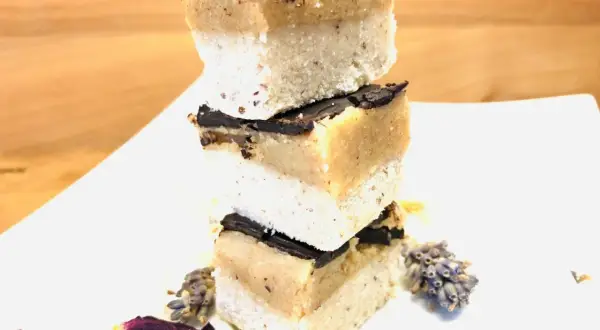Gestapelte Scheiben Millionaire Shortbread mit Schokoladenglasur, dekoriert mit Lavendel und Blütenblättern.
