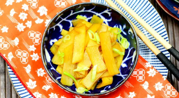 Schüssel mit goldbraunem Menma Ramen, garniert mit Frühlingszwiebeln, bereit zum Genuss mit Essstäbchen.