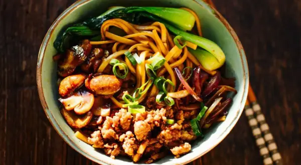 Schüssel mit Yaki Udon Nudeln, Hackfleisch, Pilzen, Pak Choi und Frühlingszwiebeln.