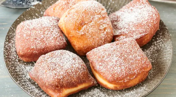Leckere, goldbraune Beignets, bestäubt mit Puderzucker. Dieses Beignets Rezept ist ein Genuss!