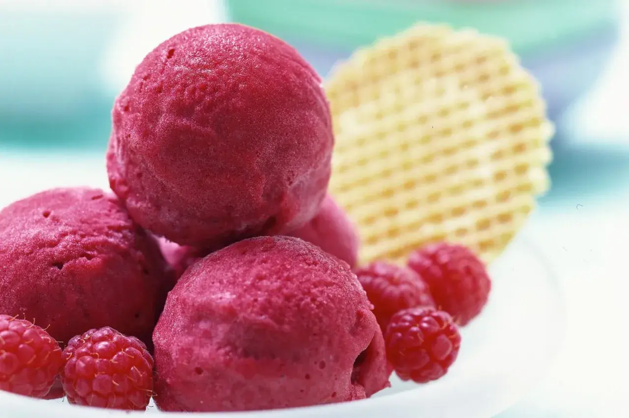 Himbeer Sorbet Kugeln mit frischen Himbeeren und Waffel. Ein erfrischender Genuss für heiße Tage.