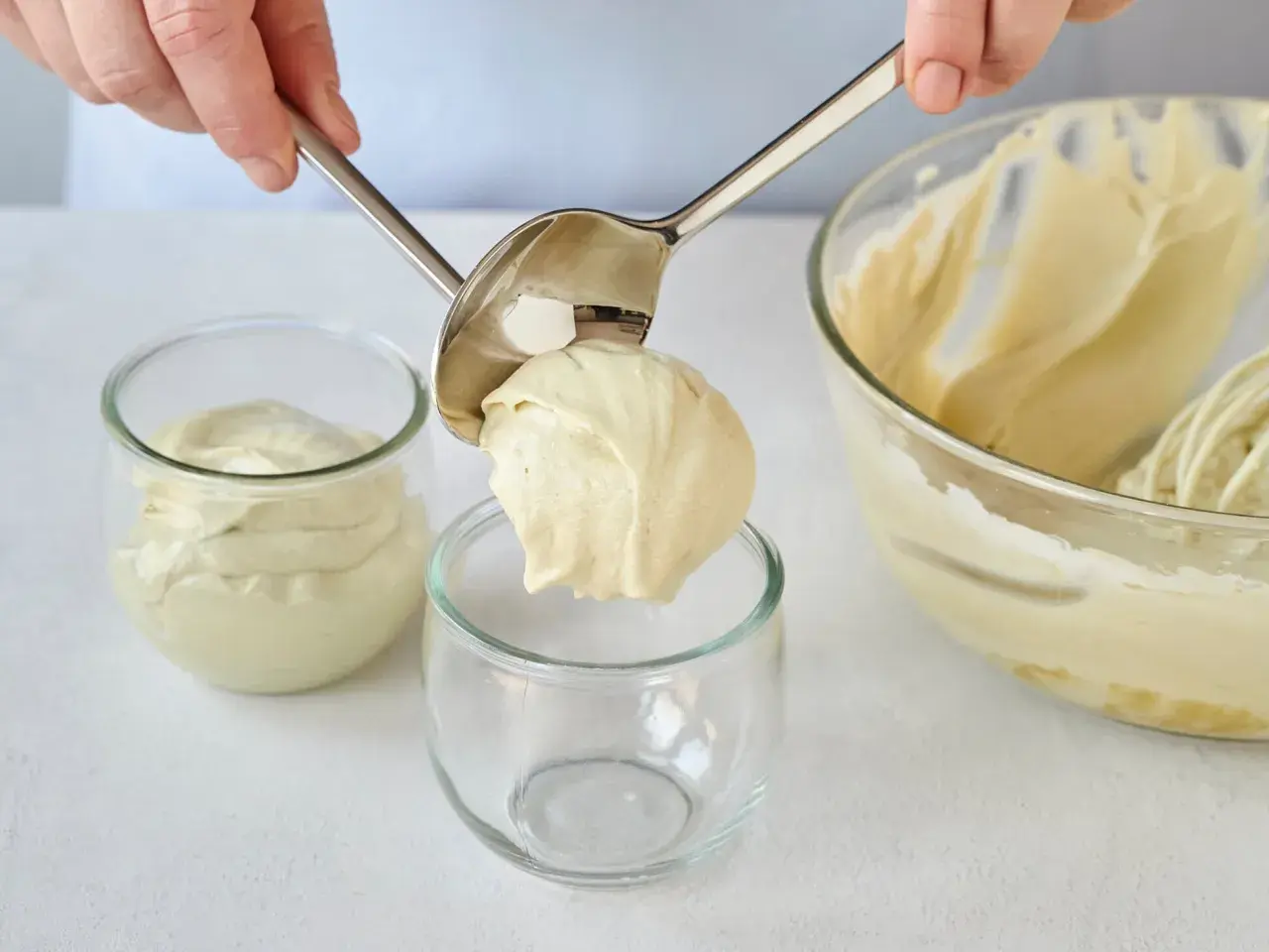 Eine Portion cremiger Pistazienmousse wird mit einem Löffel in ein Glas gegeben.
