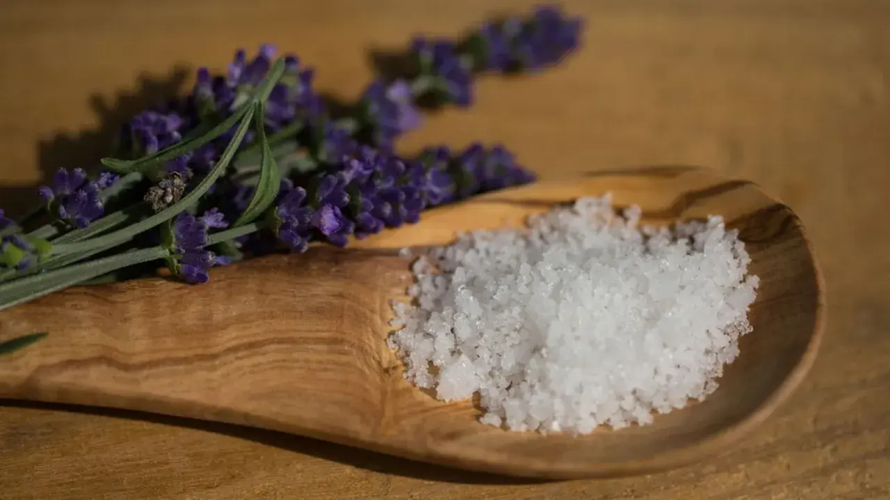Fleur de Sel, feine Meersalzkristalle, auf einem Olivenholz-Löffel neben Lavendel. Was ist Fleur de Sel? Ein Hauch von Luxus für Ihre Küche.