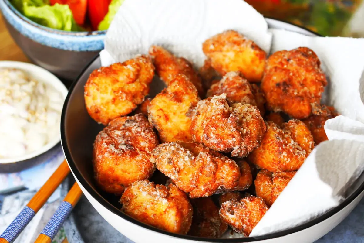 Knuspriges Chicken Karaage in einer Schüssel, daneben eine Dip-Schale und Salat. Perfekt für einen Snack!