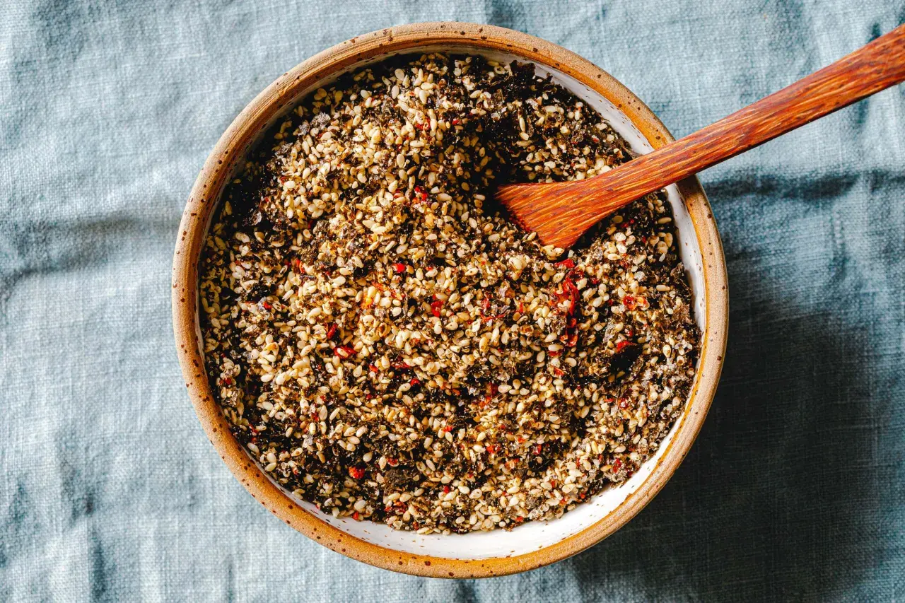 Schale mit selbstgemachtem Furikake, einer Mischung aus geröstetem Sesam, Algen und Chili. Ein Holzspatel liegt darin.