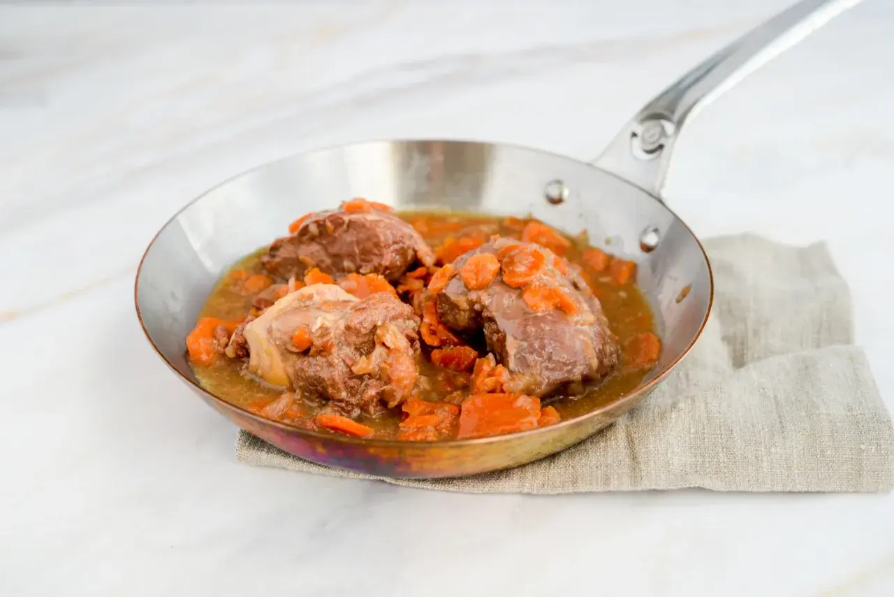 Saftige Daube de boeuf mit Karotten in einer Pfanne, serviert auf einem Leinentuch.
