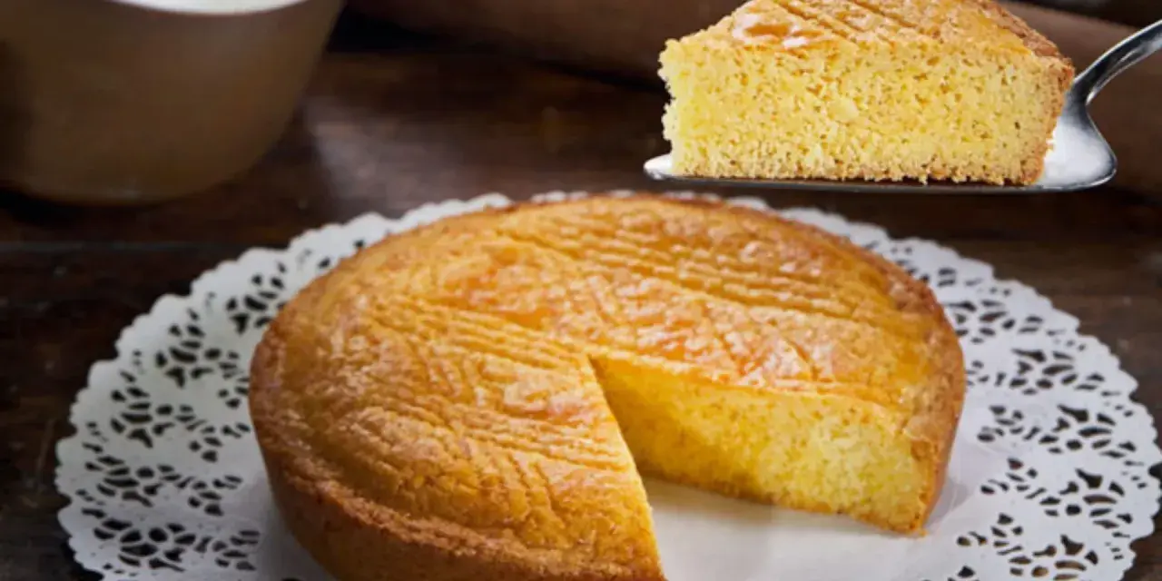 Ein goldbraunes Gateau Breton mit einem Stück auf einem Tortenheber.