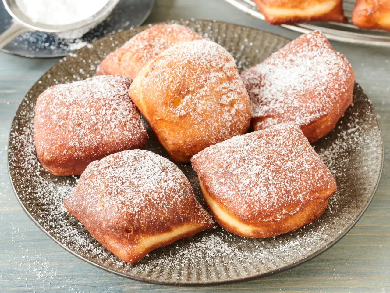 Leckere, goldbraune Beignets, bestäubt mit Puderzucker. Dieses Beignets Rezept ist ein Genuss!