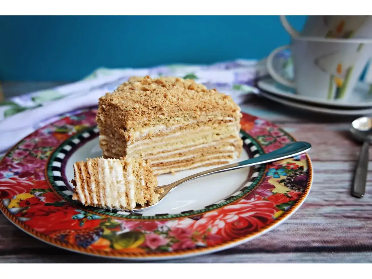 Ein St&uuml;ck russischer Kuchen, geschichtet mit Honig und Sahne, auf einem bunten Teller.