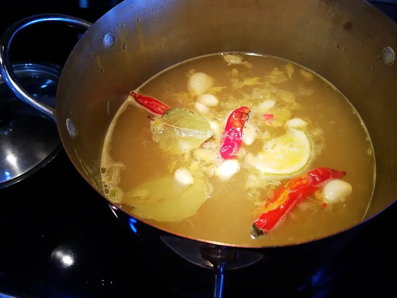 Ein Sud mit Chilis, Knoblauch und Lorbeerbl&auml;ttern k&ouml;chelt. Die Zutaten helfen, die Sch&auml;rfe des Pfeffers zu neutralisieren.