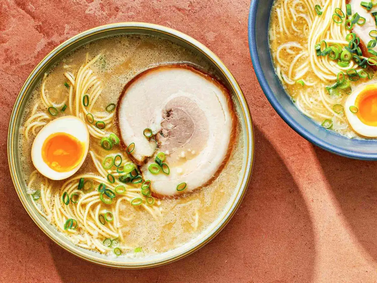 Zwei Sch&uuml;sseln dampfender Ramen, perfekt zum Ramen selbst machen. Mit Nudeln, Ei, Scheiben von Chashu-Schweinefleisch und Fr&uuml;hlingszwiebeln.