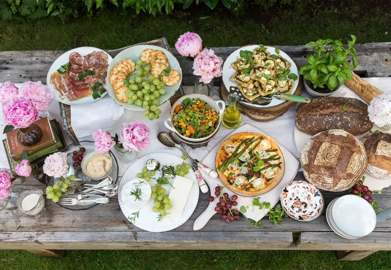 Ein Festmahl mit internationalen Gerichten: Quiche, Aufschnitt, K&auml;se, Trauben, Brot und ein bunter Salat laden zum Genie&szlig;en ein.