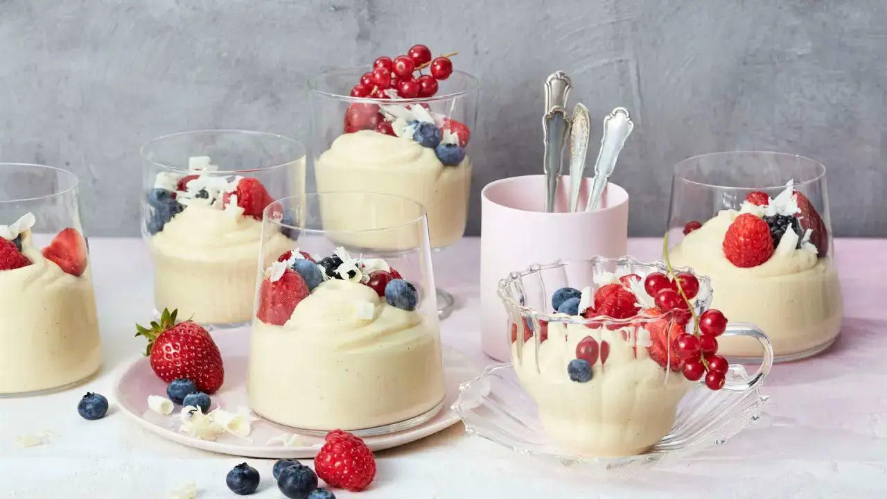 Cremiges Mousse au chocolat blanc, garniert mit frischen Beeren und Kokosraspeln, serviert in Gläsern.