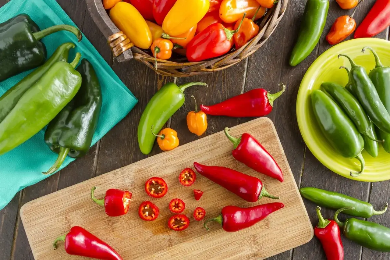 Bunte Chilis, darunter Jalape&ntilde;os und rote Sorten, liegen verstreut. Ist Pfeffer gesund? Ja, diese Vielfalt beweist es!