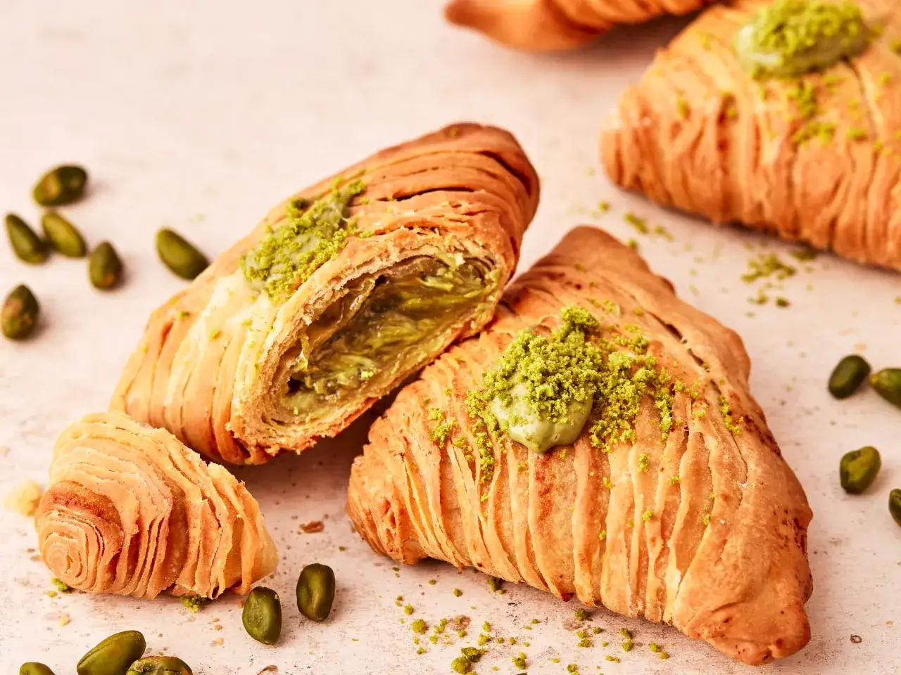 Leckereien zum Backen mit Pistaziencreme: goldbraune, geschichtete Gebäcke, gefüllt mit grüner Pistaziencreme und bestreut mit gehackten Pistazien.