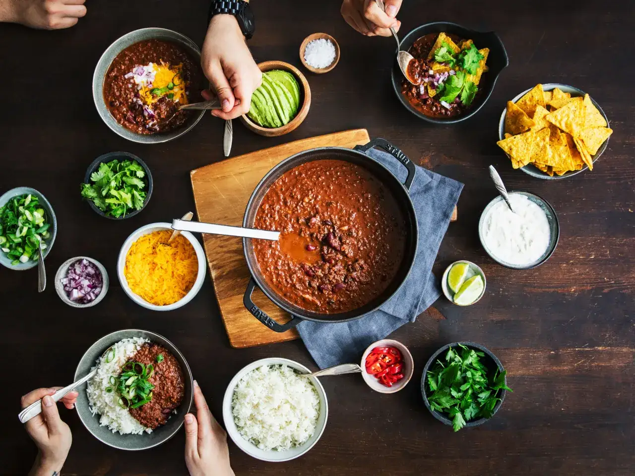 Herzhaftes Chili con Carne mit Reis, garniert mit frischen Kr&auml;utern und Beilagen wie Avocado und Nachos.