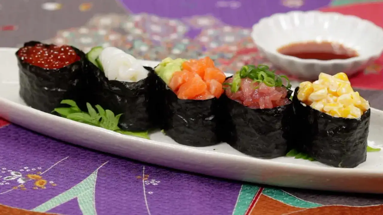 F&uuml;nf bunte Sushi Gunkan mit Lachs, Thunfisch, Mais, Kaviar und Tintenfisch auf einem wei&szlig;en Teller.