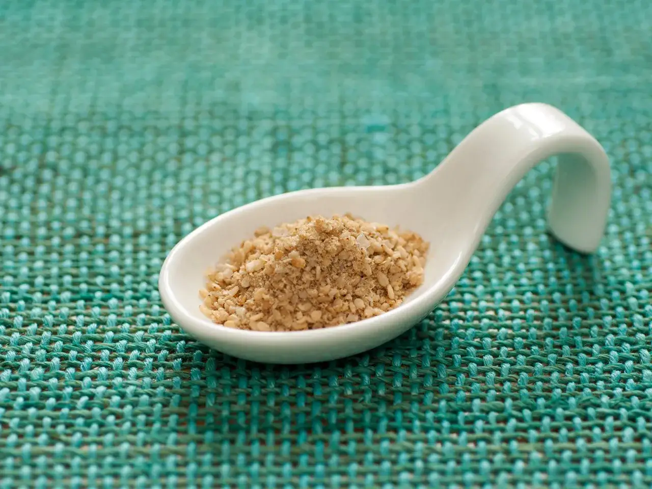 Eine L&ouml;ffelspitze voll Gomasio, perfekt f&uuml;r dein Gomasio Rezept. Die Mischung aus ger&ouml;stetem Sesam und Salz ist bereit, Gerichte zu verfeinern.
