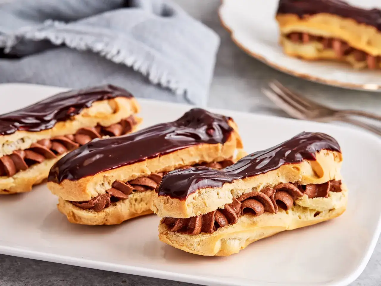 Drei k&ouml;stliche &Eacute;clairs mit Schokoladenglasur und cremiger F&uuml;llung, perfekt f&uuml;r Ihr n&auml;chstes &Eacute;clair-Rezept.