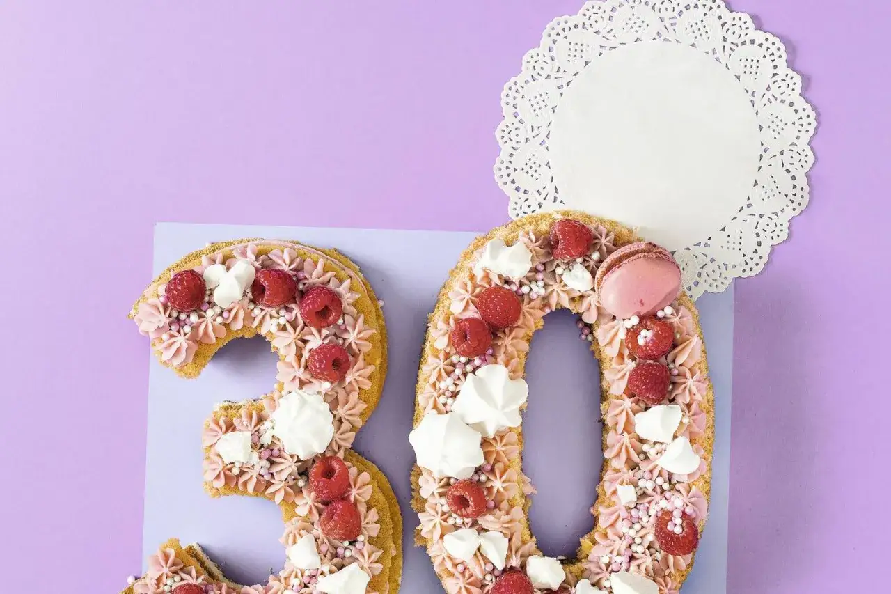Ein k&ouml;stlicher Number Cake in Form der Zahl 30, dekoriert mit Himbeeren, Baiser und rosa Buttercreme.