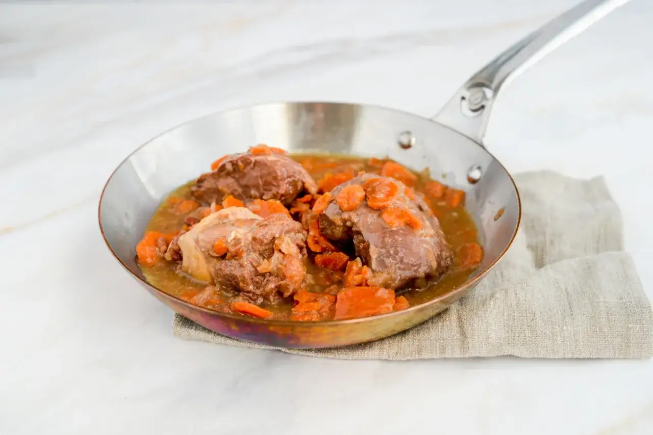 Saftige Daube de boeuf mit Karotten in einer Pfanne, serviert auf einem Leinentuch.