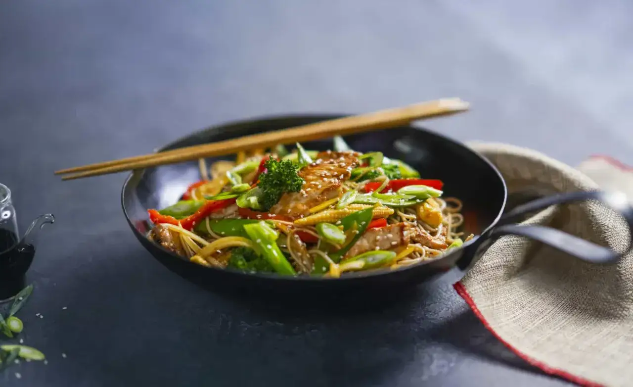 Yaki Soba mit H&uuml;hnchen und bunten Gem&uuml;sestreifen, garniert mit Sesam. Ein k&ouml;stliches Gericht, das zum Genie&szlig;en einl&auml;dt.