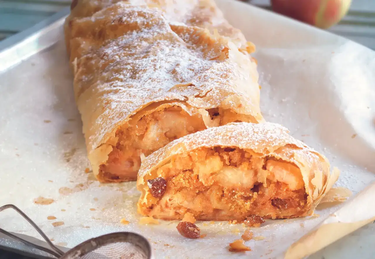 Ein goldbrauner Apfelstrudel, best&auml;ubt mit Puderzucker. Das original Apfelstrudel Rezept zeigt saftige &Auml;pfel und Rosinen.