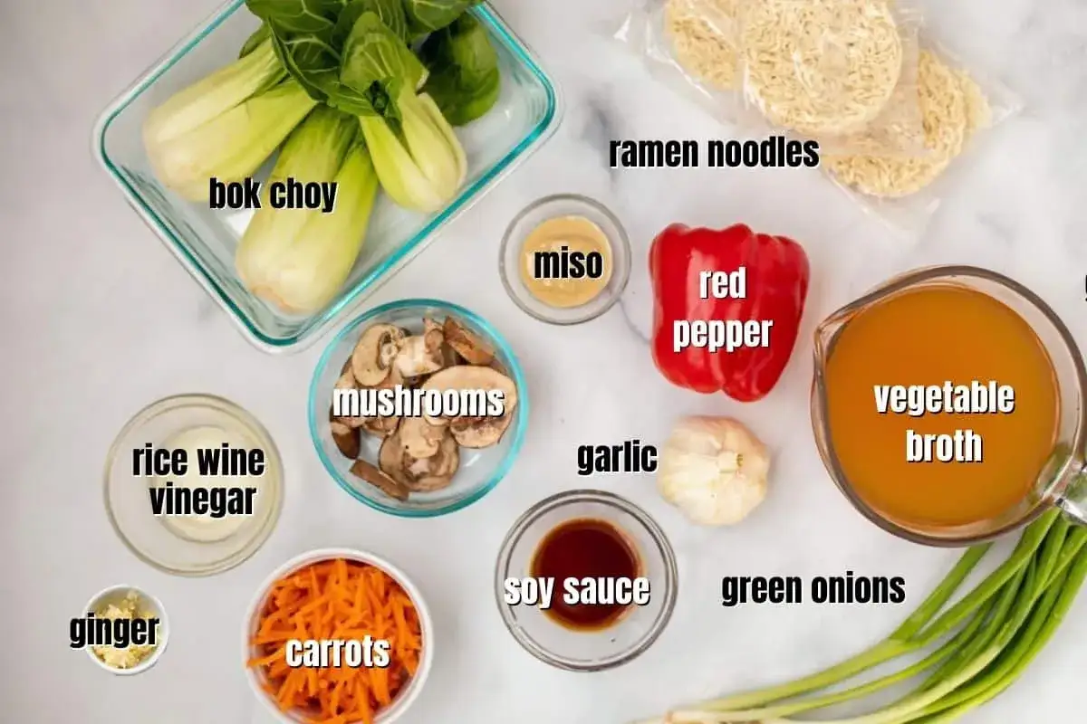 Zutaten für ein köstliches Ramen-Rezept: Bok Choy, Pilze, Karotten, rote Paprika, Ingwer, Knoblauch, Frühlingszwiebeln, Ramen-Nudeln, Gemüsebrühe, Sojasauce, Reisweinessig und Miso.
