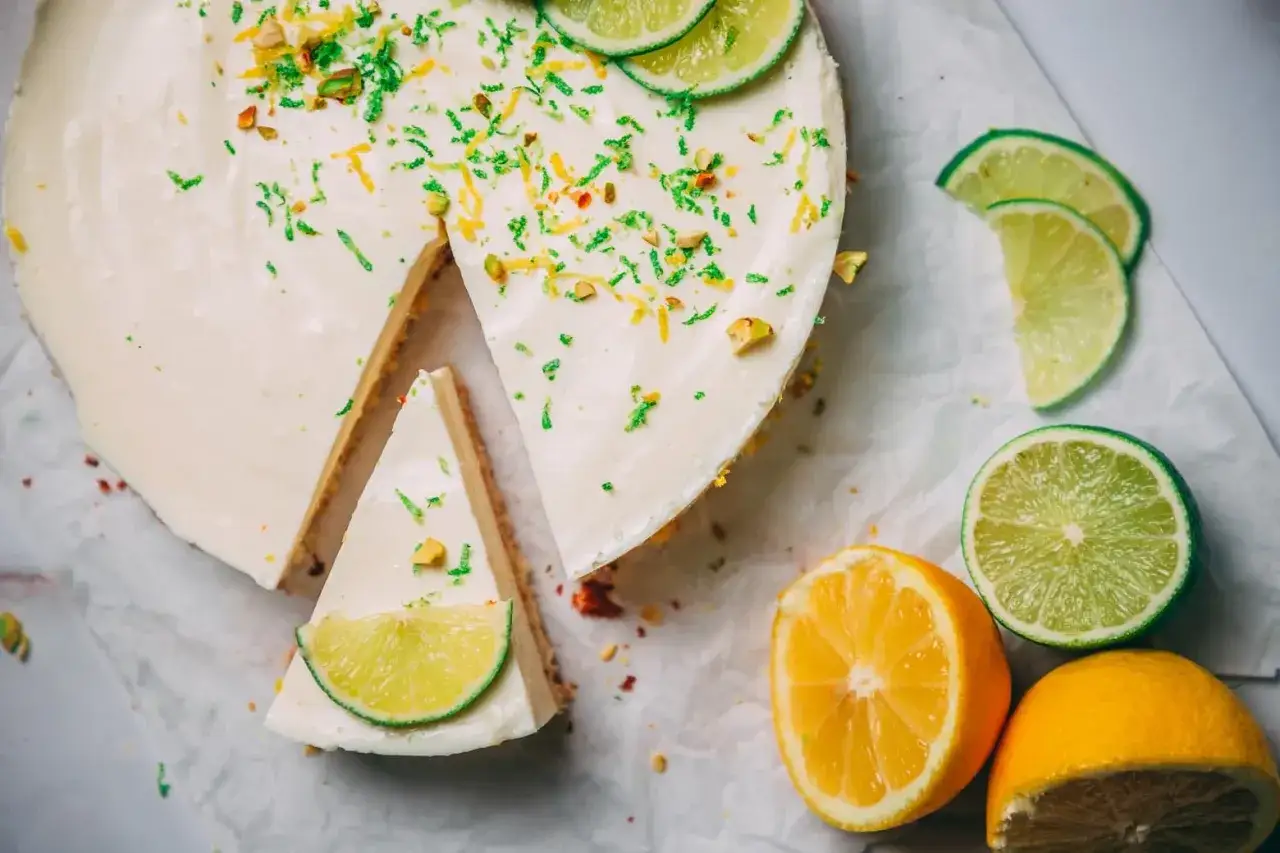 Ein cremiger Limetten Cheesecake ohne Backen, garniert mit Limettenscheiben und gehackten Pistazien. Erfrischend und leicht!