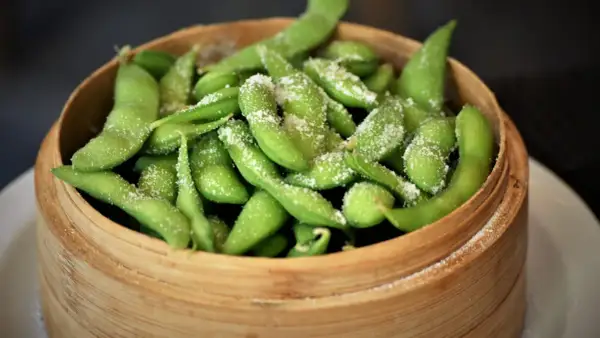 Salzige Edamame-Schoten in einem Bambuskorb. Was ist Edamame? Junge Sojabohnen, eine gesunde und leckere Vorspeise.