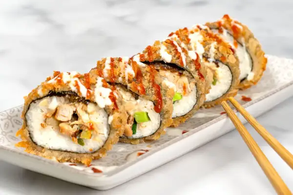 Knuspriges Sushi mit Hähnchen und Gemüse, beträufelt mit Saucen. Ein Genuss für die Sinne!