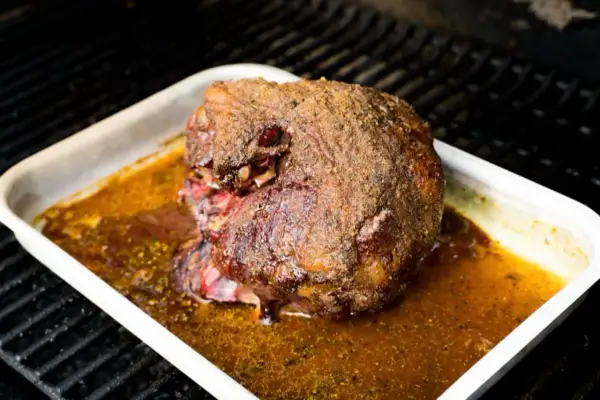 Ein saftiger Lammbraten mit knuspriger Kruste in einer Bratpfanne, bereit für ein köstliches Lammbraten Rezept.
