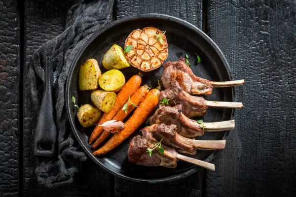 Saftiges Lammkarree mit Rosmarinkartoffeln, Karotten und geröstetem Knoblauch – das beste Rezept für einen Festtagsschmaus.