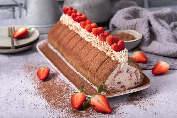 Erdbeer Tiramisu Rolle mit frischen Erdbeeren und Kakao bestäubt, ein Genuss für Augen und Gaumen.