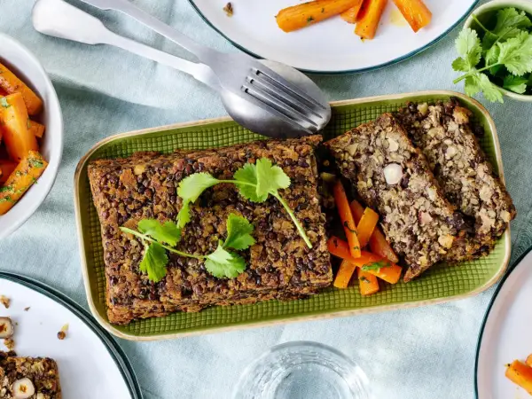 Herzhafte Linsen-Nuss-Braten, perfekt für vegetarische Rezepte Weihnachten. Dazu karamellisierte Karotten und frische Kräuter.