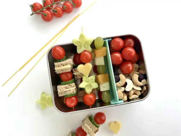 Bento-Box mit Spießen aus Mini-Sandwiches, Gurkensternen, Tomaten und Käseherzen. Ein tolles bento rezept für Kinder.