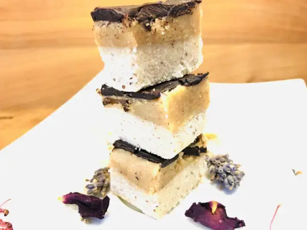 Gestapelte Scheiben Millionaire Shortbread mit Schokoladenglasur, dekoriert mit Lavendel und Blütenblättern.